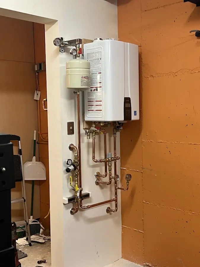 Plumbing technician inspecting water heater connections in Iona